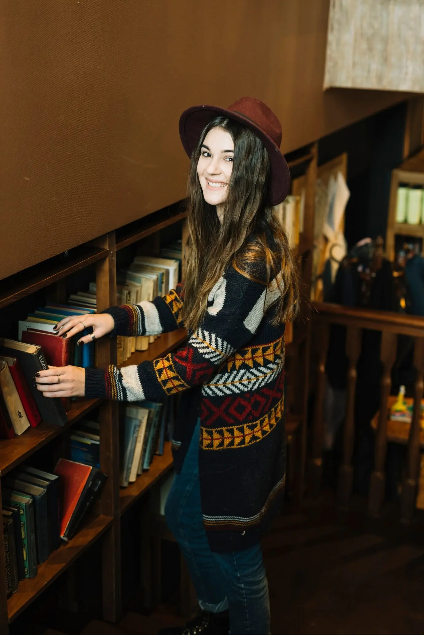 Bir kitaplığın yakınında duran genç bir kadın.